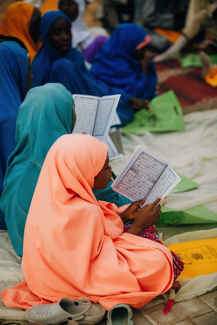 Group of children reading books outdoors, wearing colorful clothing.